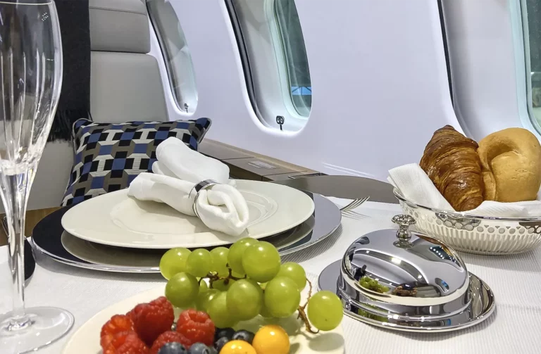 Luxurious in-flight dining setup with fresh fruits, pastries, and a glass of champagne, exemplifying a tailored flight experience.