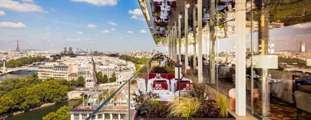 The SO/ Paris Hotel features modern architecture with panoramic rooftop views of the Paris skyline, perfect for a chic Valentine's Day escape. The elegant design and city backdrop create a sophisticated, romantic atmosphere for couples.